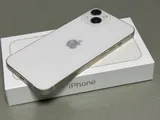 Apple iPhone 13 in starlight, rear view, resting on its retail box