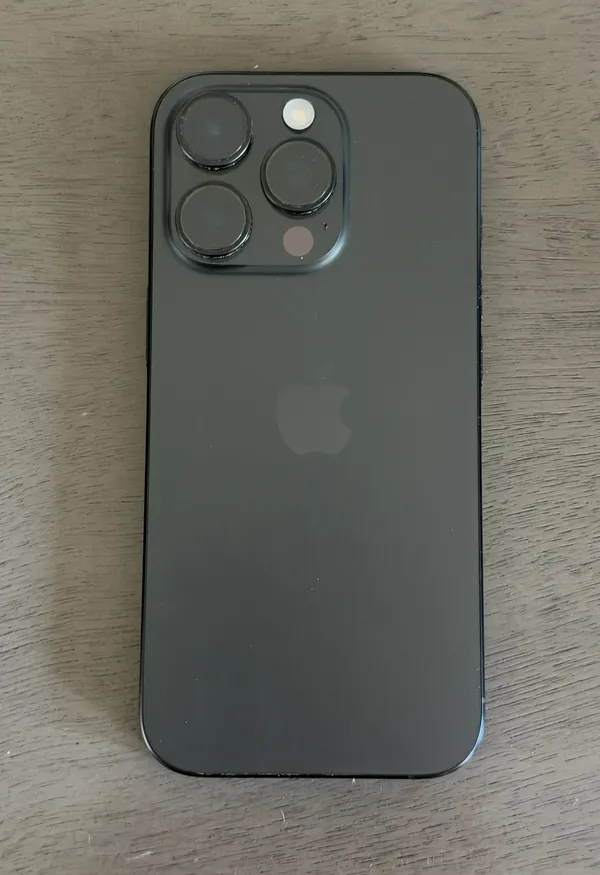 Rear of a black Apple iPhone 16 Pro lying on a table, showing its triple camera