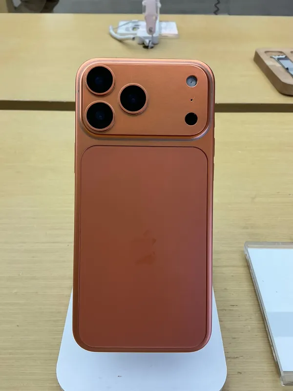 Apple iPhone 17 Pro Max in cosmic orange, rear view on a display stand