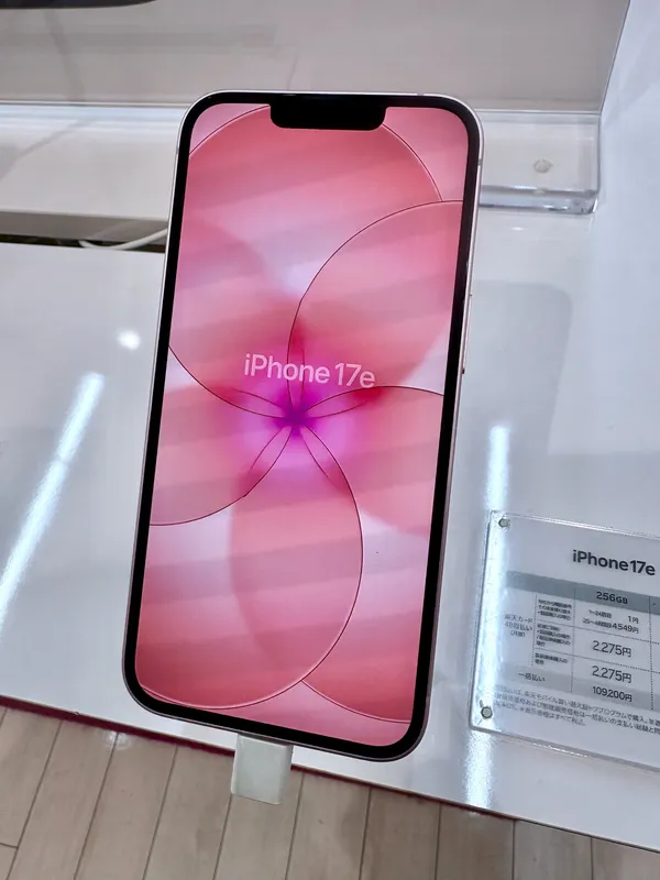 Apple iPhone 17e in soft pink, front view on a display stand